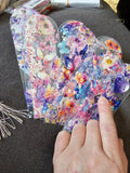 Hand holding a stack of Petite Gift Bundle - Stylish Bookmark and Pen Set on a dark surface.