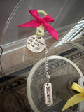 Decorative keychain with pink bow and 'BELIEVE' tag on a reflective surface