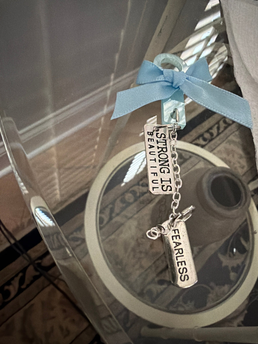 Bracelet with 'Strong is Beautiful, Fearless' charms on a reflective surface.